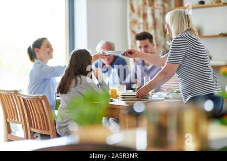 Glückliche Familie am Esstisch mit Mittag- oder Abendessen Stockfoto