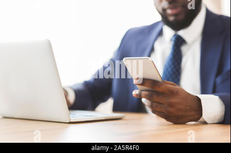 Nahaufnahme von Geschäftsmann mit Mobiltelefon am Arbeitsplatz Stockfoto