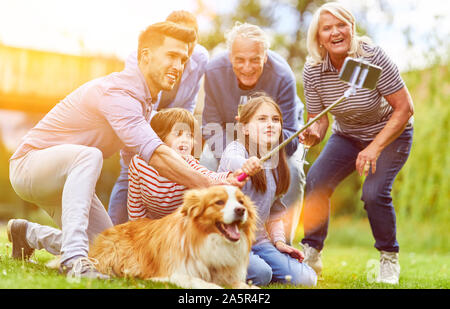 Große erweiterte Familie macht selfie im Garten mit Hund im Sommer Stockfoto