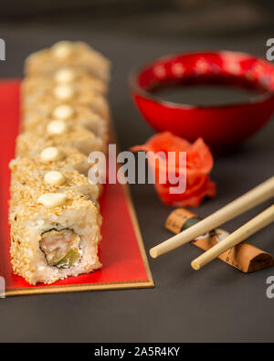 Sushi Rollen mit Sesam mit Garnelen und Avocado abgedeckt Stockfoto