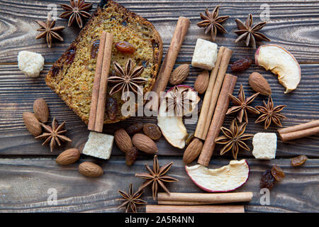 Herbst Kürbis würzen. Hausgemachte würziger Kürbiskuchen Schichten mit Walnüssen, brauner Zucker, Anis Sterne, Rosinen, Zimt auf rustikalen Holzmöbeln braunen Hintergrund. Stockfoto