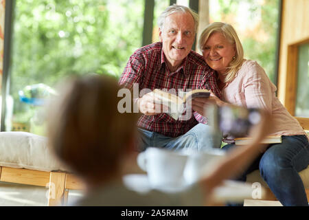 Enkelkind fotografiert seine Großeltern im Wohnzimmer als Erinnerung Stockfoto