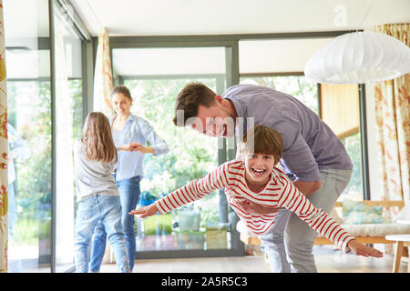 Die Eltern spielen und toben mit ihrer glücklichen Kinder im Wohnzimmer Stockfoto