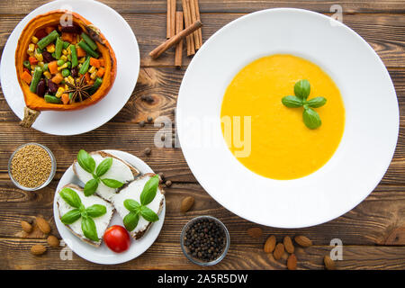 Kürbis creme Suppe mit Basilikum, gebackener Kürbis mit Gemüse: Karotten, Bohnen, Weiße, Bruschetta mit Frischkäse und Tomaten. Danksagung Stockfoto