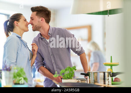 Junger Mann küsst seine Freundin in der Küche beim Kochen Stockfoto