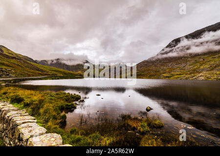 Noch Reflexionen und niedrige Wolken über Llyn Ogwen, Snowdonia National Park, North Wales, UK Stockfoto