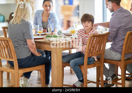Junge am Esstisch beim Mittagessen mit Eltern und Großeltern gelangweilt Stockfoto