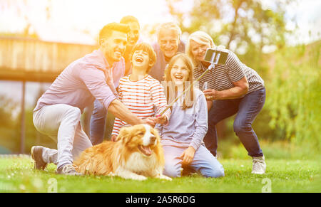 Lachend Familie macht selfie im Garten mit Kinder, Großeltern und Hund Stockfoto