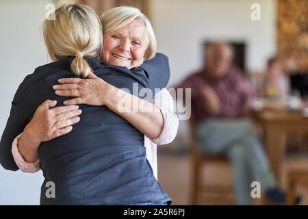 Senior umfaßt ihre Tochter am Willkommen zu Hause oder im Pflegeheim Stockfoto