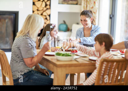 Mutter mit Kindern und Oma in Mittag- oder Abendessen am Esstisch Stockfoto