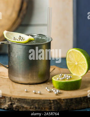 Kaltes Wasser mit Eis und Zitrone Zitronenschale in Becher Edelstahl Stockfoto