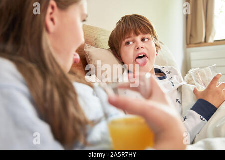 Naughty Boy zeigt seine Schwester die Zunge am Morgen beim Frühstück im Bett Stockfoto