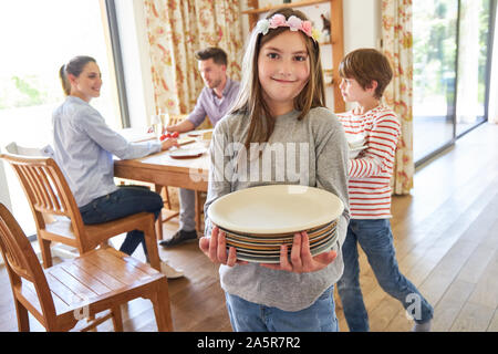 Mädchen hilft mit der Hausarbeit und trägt Gerichte im Wohnzimmer Stockfoto