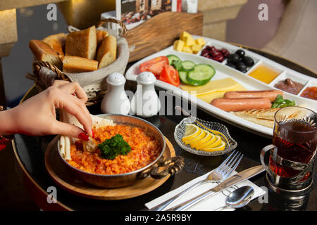 Frau Hand tauchen Brot auf Ei und Tomate Teller zum Frühstück serviert Setup Stockfoto