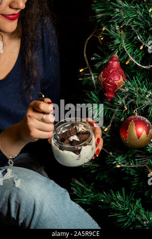 Frau Schokolade essen Kuchen Würfel in Sahne aus Glas Stockfoto