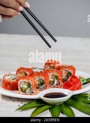 Frau mit Stäbchen sushi Rollen mit roten tobiko zu nehmen Stockfoto