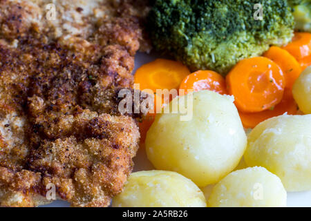 Schweinekotelett mit gekochtem Gemüse, Kartoffeln und Zwiebeln. Österreichische Schnitzel mit Beilage. Ansicht von oben, aus der Nähe. Stockfoto