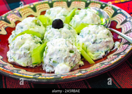 Bulgarischen traditionellen Salat aus Joghurt und Gurken, genannt Snezhanka oder Milch Salat auf das bulgarische rote Tischdecke Stockfoto