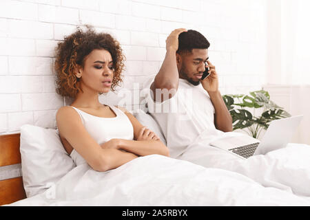Afrikanische Frau im Bett lag, mit ihr am Telefon sprechen Mann beleidigt Stockfoto
