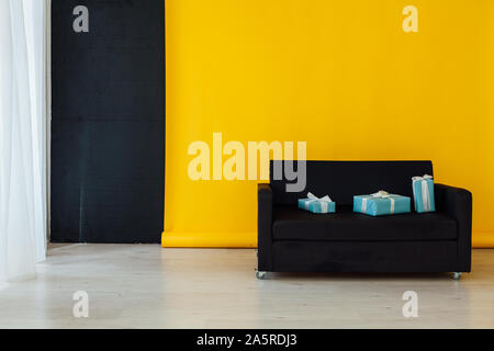 Schwarzes Sofa mit Geschenken in die Innenausstattung des Zimmers mit einem gelben Hintergrund Stockfoto