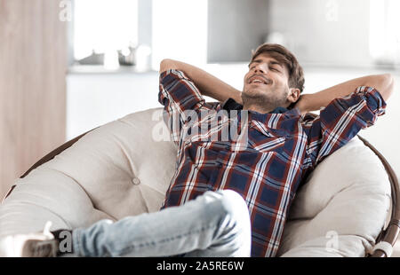 Brütende junge Mann auf einem Stuhl sitzend Stockfoto