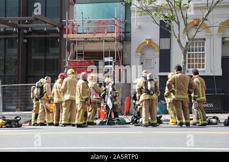 Auckland, Neuseeland. 22 Okt, 2019. Feuerwehrmänner sammeln an der Unfallstelle von einem Brand in Auckland, Neuseeland, Okt. 22, 2019. Ein massives Feuer ausgebrochen Dienstag Nachmittag an einer Baustelle im neuseeländischen Auckland City Centre hat eine fehlende und eine weitere schwer verletzt. Credit: Xu Liming/Xinhua/Alamy leben Nachrichten Stockfoto