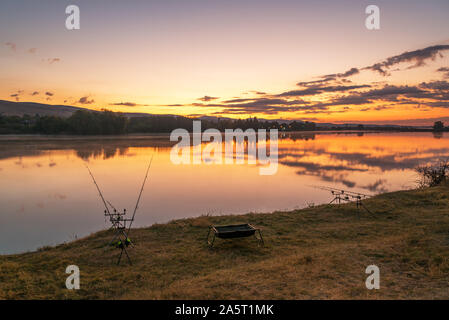 Karpfen angeln karpfen beißen Indikatoren und Rollen auf rod pod in der Nähe des Flusses. Angeln bei Sonnenaufgang. Stockfoto