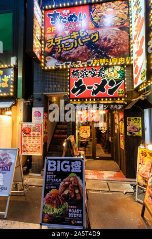 Tokio, Akihabara. Menü Boards auf Pflaster für Ramen Restaurant Eingang im Erdgeschoss und Rindersteak Hamburger Restaurant im zweiten Stock. In der Nacht. Stockfoto