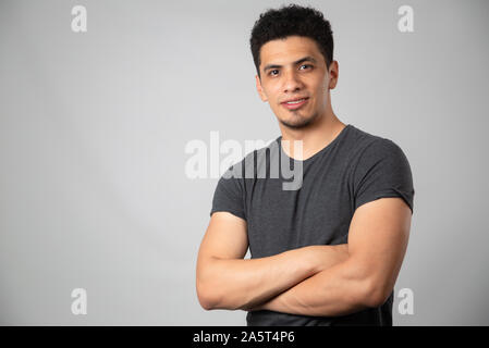 Hispanic Mann lächelnd im Studio mit grauem Hintergrund Stockfoto