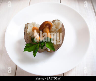 Eingelegte Pilze auf gekochte Kartoffeln und eine weiße Platte Stockfoto