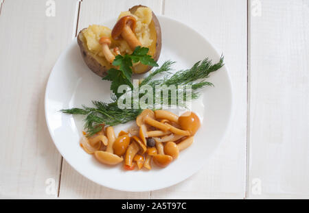 Eingelegte Pilze auf gekochte Kartoffeln mit Kräutern Stockfoto