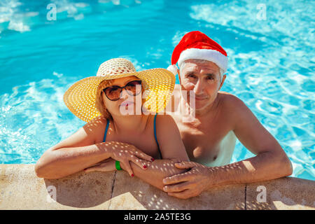 Neues Jahr und Weihnachten feiern. Mann in Santa's Hut und Frau entspannen im Pool. Tropischer Urlaub Familienurlaub Stockfoto