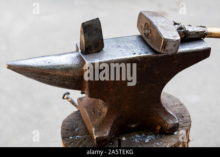 Mit einem Hammer und einem Metallteil auf einen Amboss. Werkzeuge und Gegenstände aus Metall von der Schmied in einer Schmiede verwendet. Stockfoto