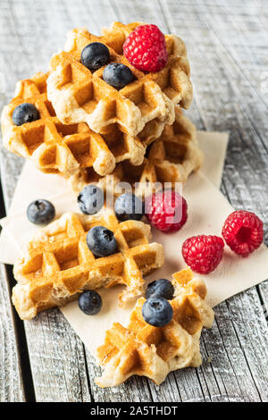 Waffeln mit Heidelbeeren und Himbeeren auf weissem Holztisch. Stockfoto