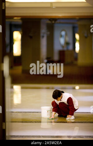 Mitte der erwachsenen Frau Reinigung der Fußboden in der Lobby. Stockfoto