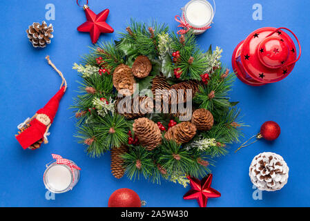 Weihnachtsdekoration mit Tannenzweigen und Kegel von glänzenden Kugeln, Sternen umgeben, Tannenzapfen, Puppe, Kerzen und Laternen. Stockfoto