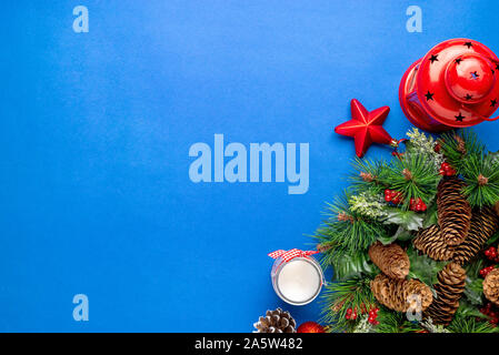 Weihnachtsdekoration auf der blauen Fläche. Tannenzweigen mit Tannenzapfen. Kerzen und Laternen neben. Kopieren Sie Raum, Flach, Ansicht von oben. Stockfoto