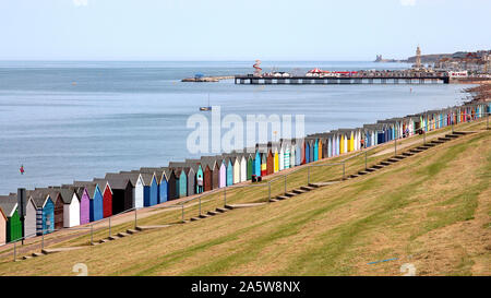 Blick von der Western Esplanade, Herne Bay von Dutzenden gayly lackiert Strand Hütten entlang der Strandpromenade. In der Nähe befindet sich der Glockenturm und die Pier. Stockfoto