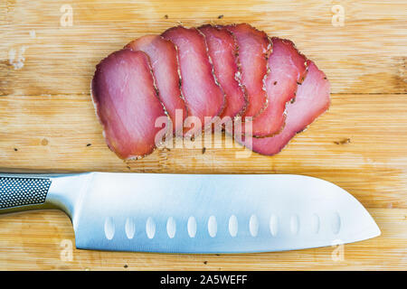 Stücke geschnitten ruckartig auf einer hölzernen Schneidebrett mit Santoku Messer Nahaufnahme. Bär Fleisch Snack Stockfoto