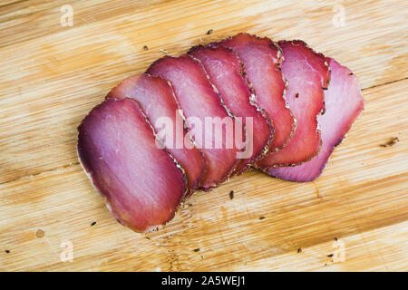 Stücke geschnitten ruckartig auf einer hölzernen Schneidebrett mit Spice Nahaufnahme. Bär Fleisch Snack Stockfoto