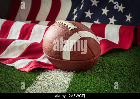 Fußball auf einem grünen Feld mit weißem Streifen und die amerikanische Flagge hinter Stockfoto