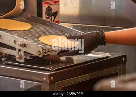 Hand ausstrecken wie Tortillas Ausrollen einer Maschine in einer Taqueria Stockfoto