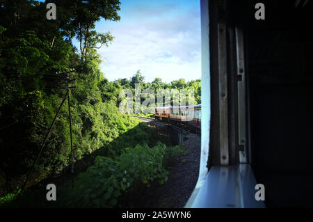 Blick aus dem Zug Bahn macht eine Kurve durch eine wunderschöne natürliche grüne Wiesen und Berge biegen. Reisen in Thailand Stockfoto