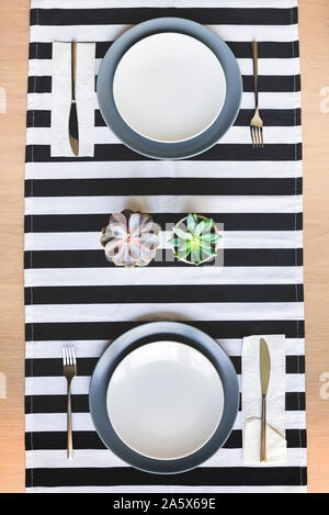 Blick von oben auf die gedeckten Tisch für Zwei. Minimalistischer Dekoration mit saftigen Blüten. Stockfoto
