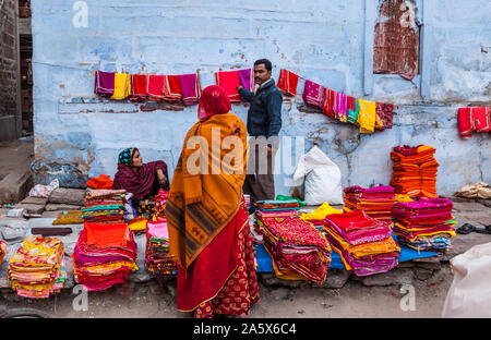 Ein Mann Verkauf von Textilien zu einem Kunden bei einem open air Street Market in Jodhpur, Rajasthan, Indien. Stockfoto