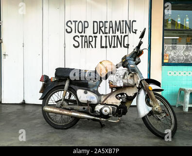 Hören Sie auf zu träumen zu leben beginnen Zitat Slogan auf Hintergrund mit alten Motorrad im Vordergrund Stockfoto