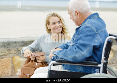 Erwachsene Tochter drücken senior Vater im Rollstuhl Stockfoto