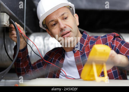 Elektriker die Messung der Spannung der Kabel an der Decke im Innenbereich Stockfoto