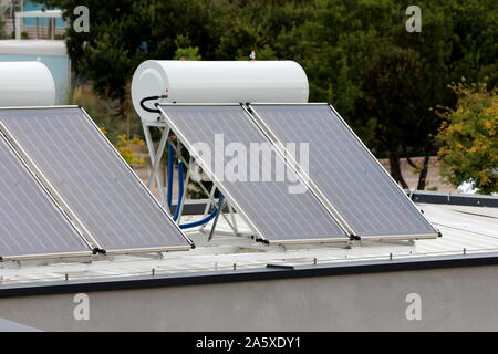 Neue Solaranlage für Warmwasser auf dem Dach der örtlichen Tourist Resort mit dichten Bäumen auf warmen sonnigen Sommertag umgeben installiert Stockfoto
