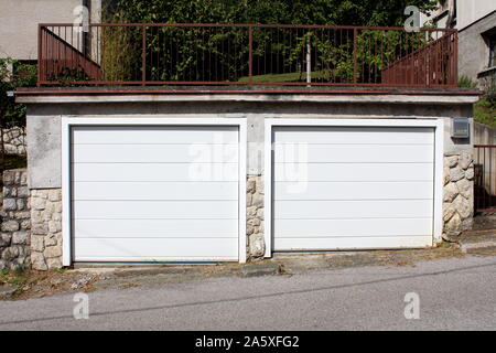 Zwei weiße Garagentore und Fenster im blauen Haus Stockfoto, Bild